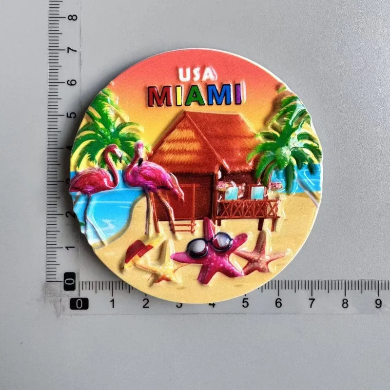 A circular magnet featuring a tropical scene with flamingos, palm trees, and a beach under the USA Miami title.