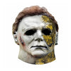 A realistic latex mask of Michael Myers featuring a pale face, yellow staining, and bloody scar details.
