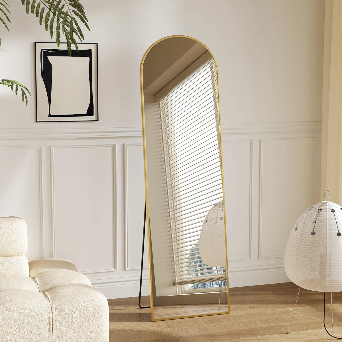 A tall floor mirror with a gold frame and vertical slats reflects a room interior.
