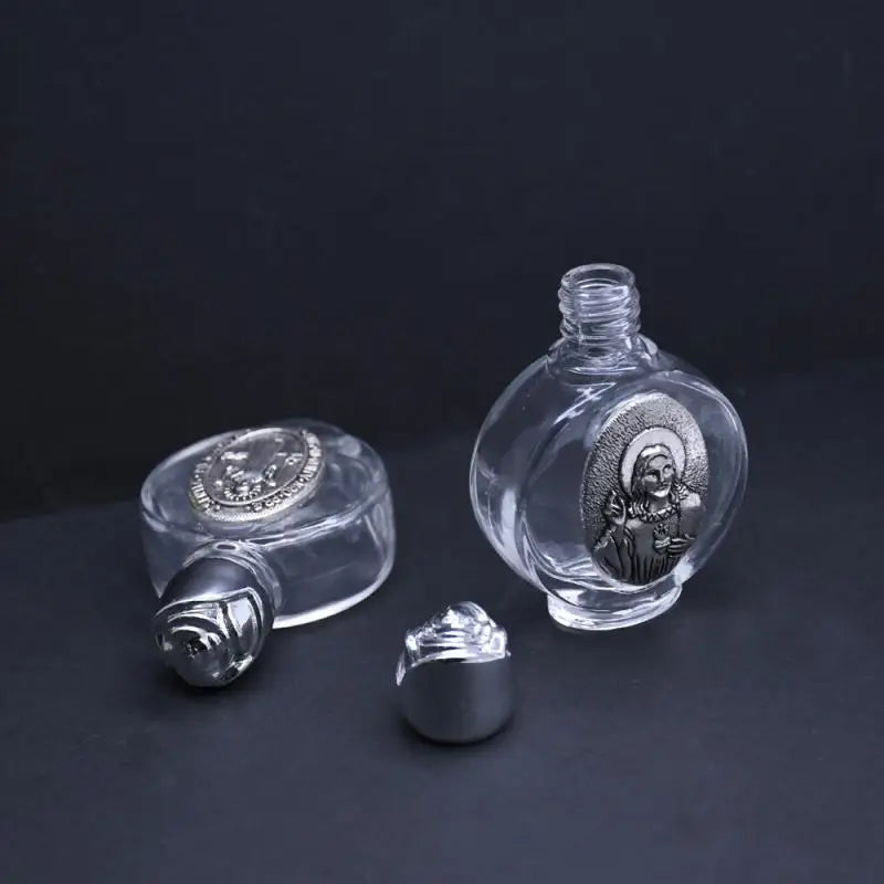 A clear glass bottle with a rounded body, featuring an engraved figurine and a decorative twist cap.
