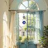 A light blue wooden door with glass panels and curtains in a bright interior setting.