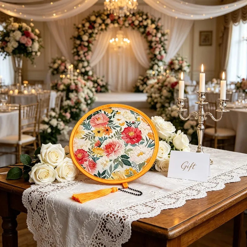 A wooden table set for an event featuring a floral pocket fan and white lace tablecloth.