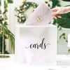 A white acrylic gift box with the word cards engraved on the front, being opened by a hand.