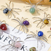 Handcrafted crystal spider figurines with various colored stones displayed on a light background.