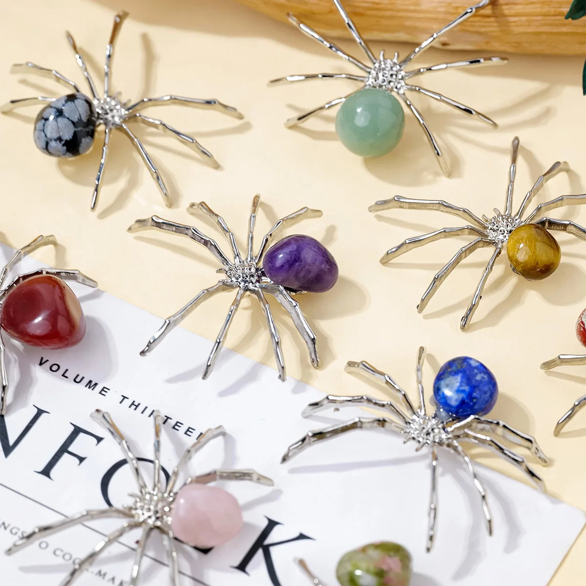 Handcrafted crystal spider figurines with various colored stones displayed on a light background.