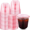 A stack of pink disposable plastic cocktail cups is shown, with one cup filled with a dark liquid.