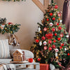 A decorated Christmas tree adorned with red and white ornaments, including snowflake designs, in a cozy indoor setting.