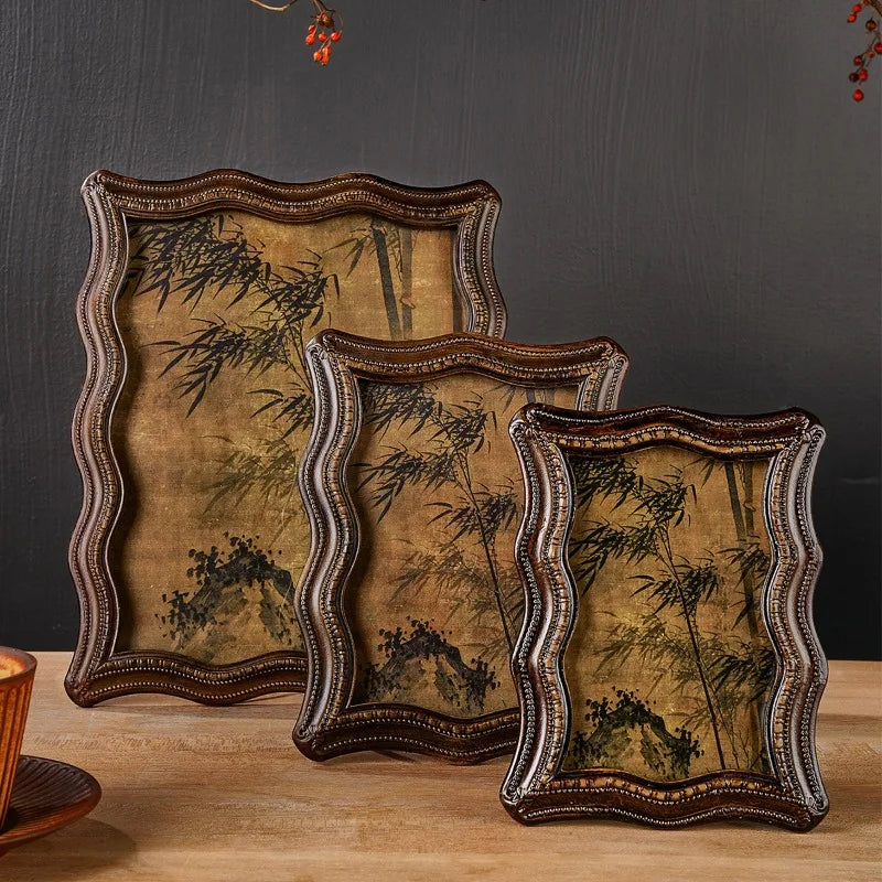 A set of three vintage resin photo frames with distressed gold and olive green tones displayed on a wooden surface.