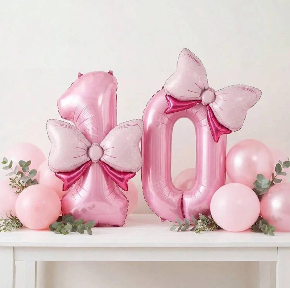 Pink foil number balloons shaped like the number 8 and 0 with bow accents