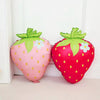 Two pink and red strawberry foil balloons with green leaves and white flowers