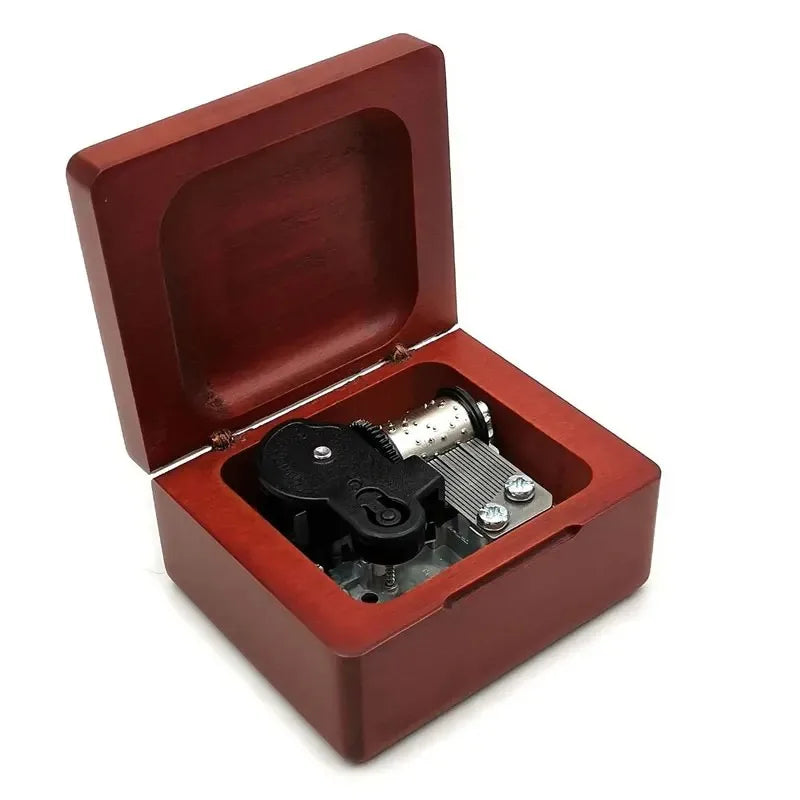 A wooden music box with a reddish-brown lid open, revealing the internal mechanism.