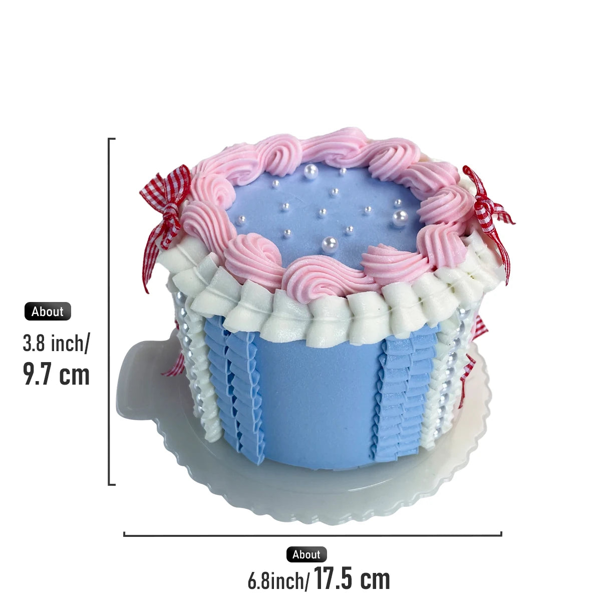 A round light blue decorative fake cake with pink frosting swirls and red ribbon accents.
