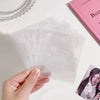 A hand holds a stack of clear glitter star cards for collectibles on a white surface.