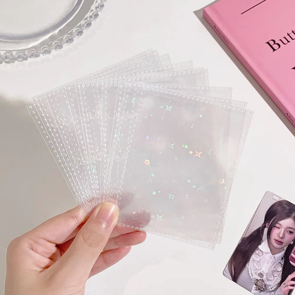 A hand holds a stack of clear glitter star cards for collectibles on a white surface.