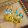 A gold crystal rhinestone crown featuring blue gemstones and animal motifs displayed in a box.