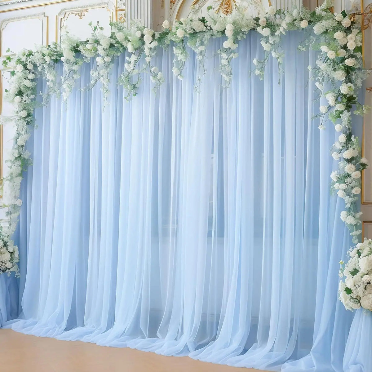 Tela transparente azul claro con guirnaldas florales blancas creando un fondo suave para un evento