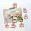 Pink cherry blossom fridge magnets with white accents displayed on a card.