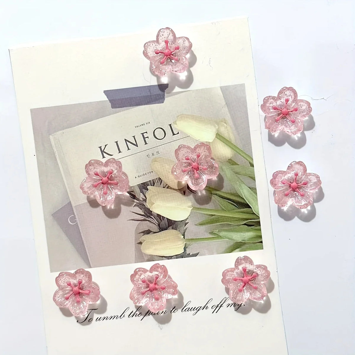 Pink cherry blossom fridge magnets with white accents displayed on a card.