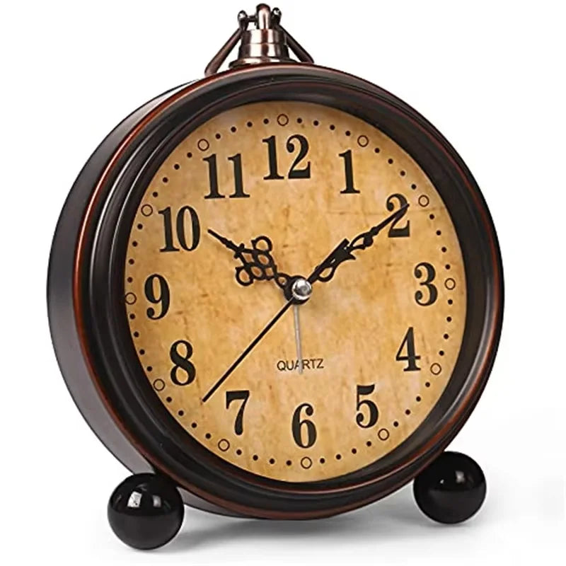 A vintage metal battery alarm clock with a round face and Roman numerals, featuring a dark brown casing and gold-toned hands.