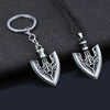 Silver metal keychain featuring an arrow design with a heart detail on a black fabric background.