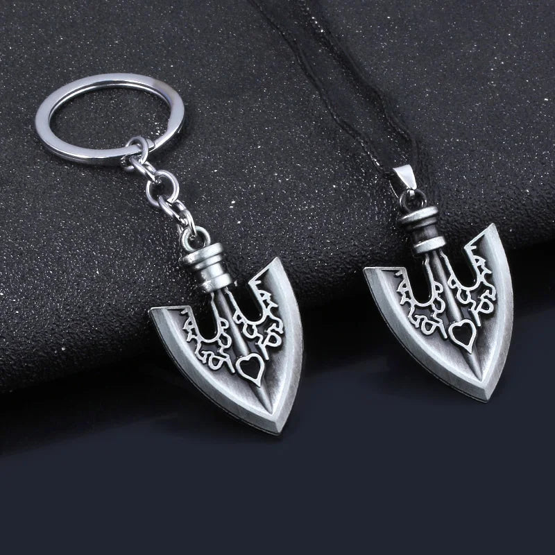Silver metal keychain featuring an arrow design with a heart detail on a black fabric background.