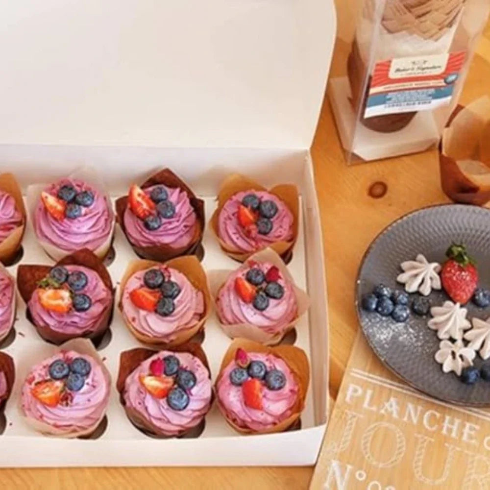 A box filled with purple and pink cupcakes in brown liners, arranged for sale.
