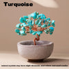 Turquoise crystal tree with blue stones mounted on a copper wire base in a light gray bowl.