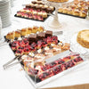 Clear acrylic cake stand with a lid displaying rectangular marbleized desserts and pastries.