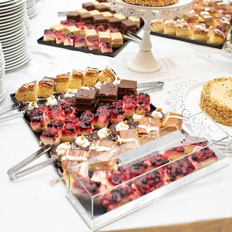 Clear acrylic cake stand with a lid displaying rectangular marbleized desserts and pastries.