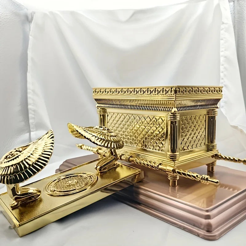 A golden metal statue of the Ark of the Covenant resting on a rectangular base.