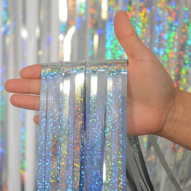 A hand holds a set of metallic foil tinsel fringe strands against a sparkly backdrop.