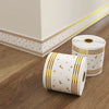 Roll of white self-adhesive PVC skirting board trim with gold foil star pattern on a wooden floor.