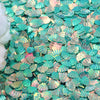 A pile of iridescent teal and pink seashell-shaped confetti or sequins for a party decoration.