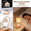 A close-up of a gold-toned, flameless decorative candle warmer lamp with a wooden base and glass diffuser.