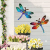 Vintage dragonfly wall art sculpture with iridescent blue and green wings displayed above fresh spring flowers.