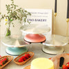 A display of silver and pink aluminum cake turntables with fresh strawberries on a table.