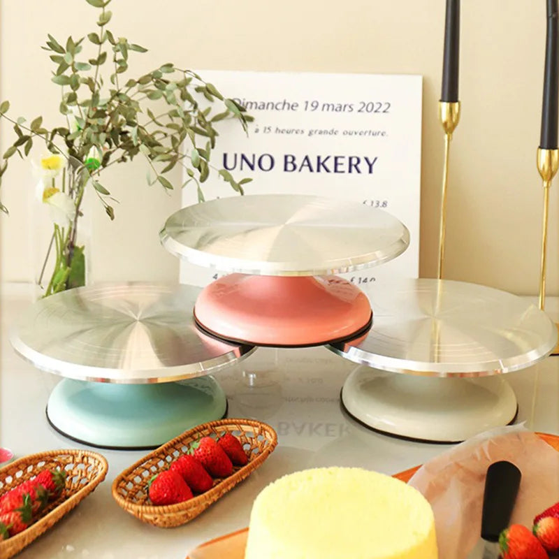 A display of silver and pink aluminum cake turntables with fresh strawberries on a table.