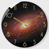 A round wall clock face showing a night sky or galaxy background with gold hour markers and hands.