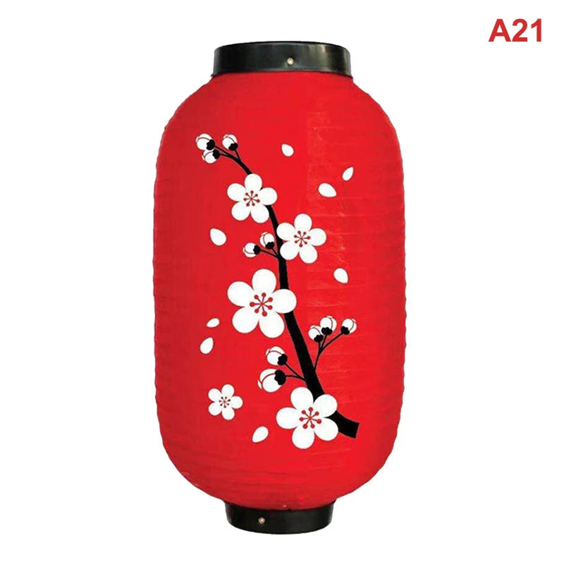 A red paper hanging lantern decorated with white cherry blossoms and branches.
