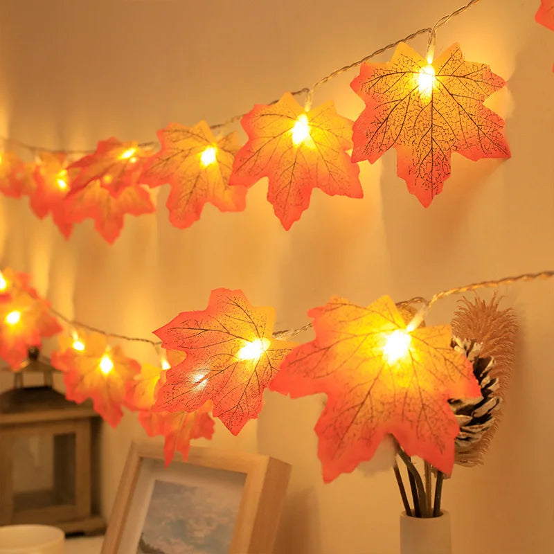 An autumn leaf garland with LED lights is displayed against a light wall, featuring orange and yellow tones.