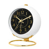 A minimalist gold-framed analog alarm clock with a white face and black dial displaying the time.