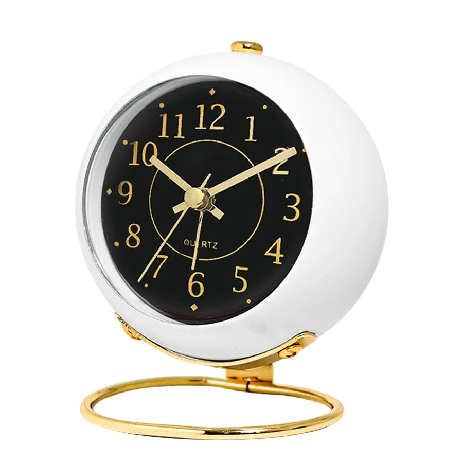 A minimalist gold-framed analog alarm clock with a white face and black dial displaying the time.