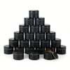 A stack of black metal candle tins with lids arranged in a pyramid formation.