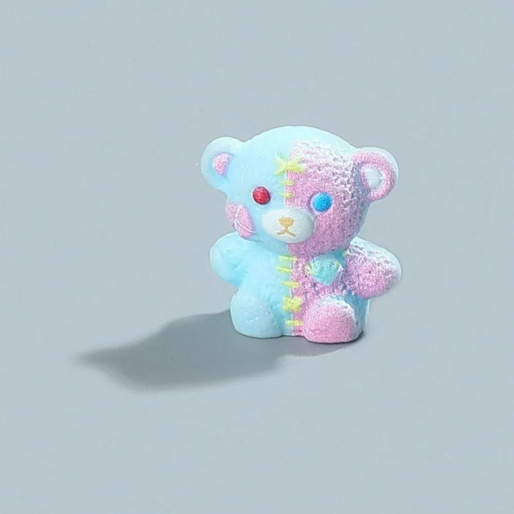 A small, soft blue and pink resin figurine of a bear with a wounded appearance.