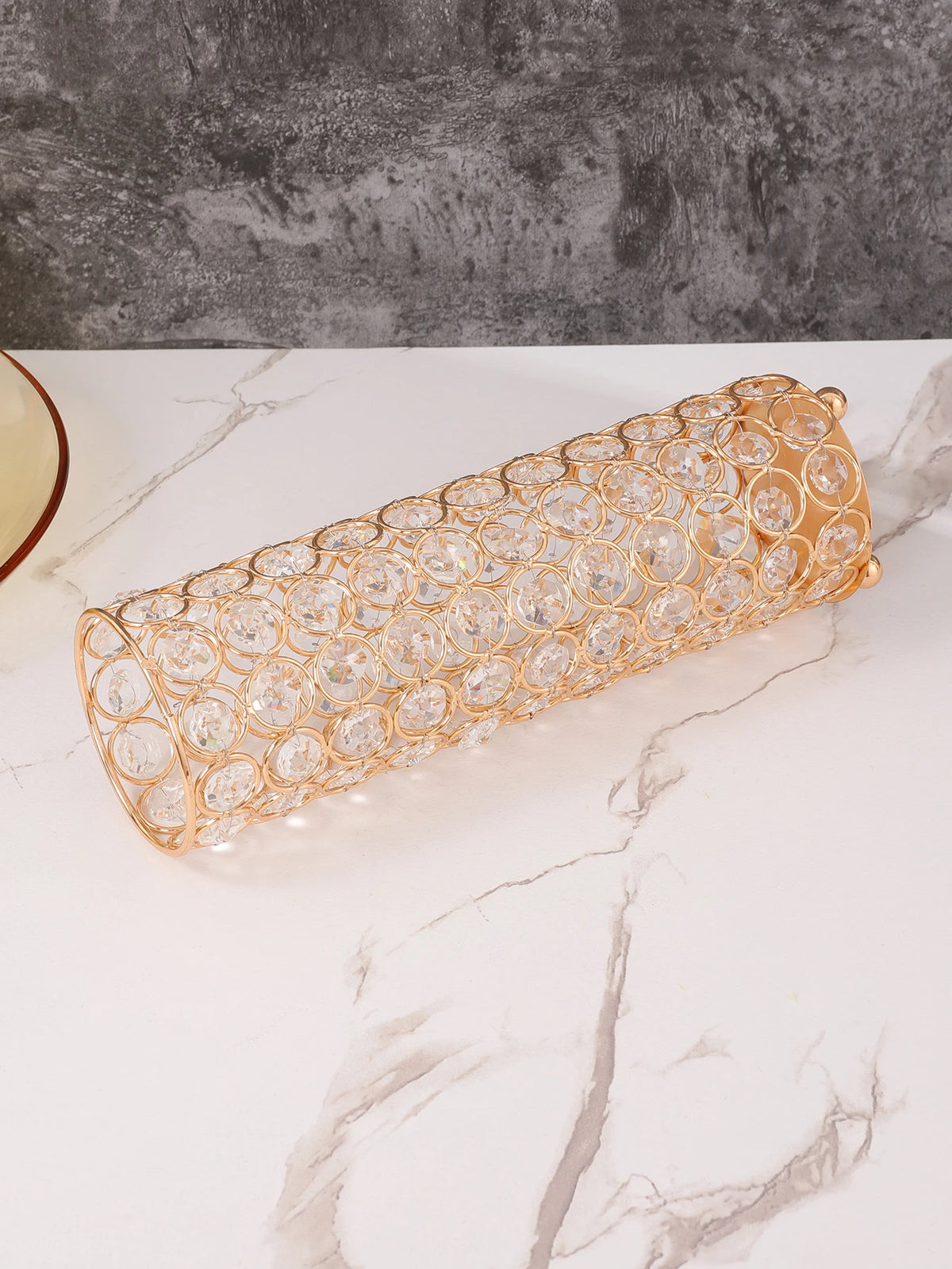 A long, cylindrical vase covered in gold wirework and clear crystals for elegant home decor.