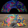 A folding rave hand fan featuring vibrant fluorescent UV glow patterns in pink, blue, green, and yellow.
