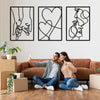 A couple sitting on a couch in front of three framed black line art prints depicting holding hands, love, and kissing motifs.