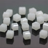A collection of white square cut glass crystal beads scattered on a dark surface.