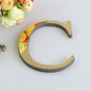 A golden letter C cutout with a gray border and floral elements on a white background.