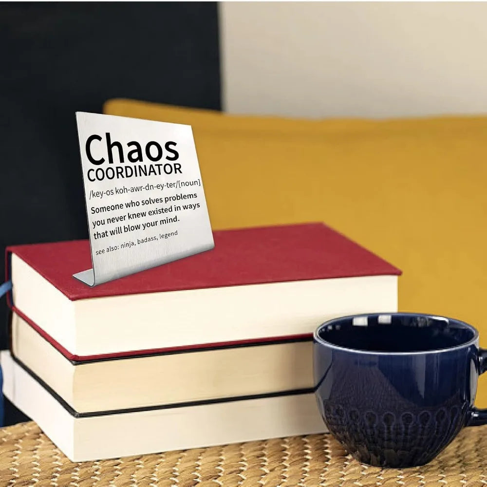 Una pila de libros con una tarjeta de título para decoración de escritorio Chaos Coordinator sobre una superficie de madera.